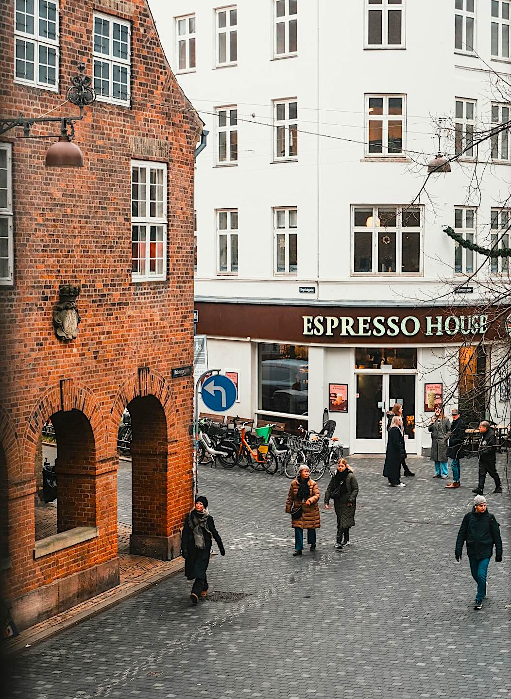 Street view of Copenhagen with people walking on cobblestone street, showcasing urban exploration and pedestrian-friendly city life